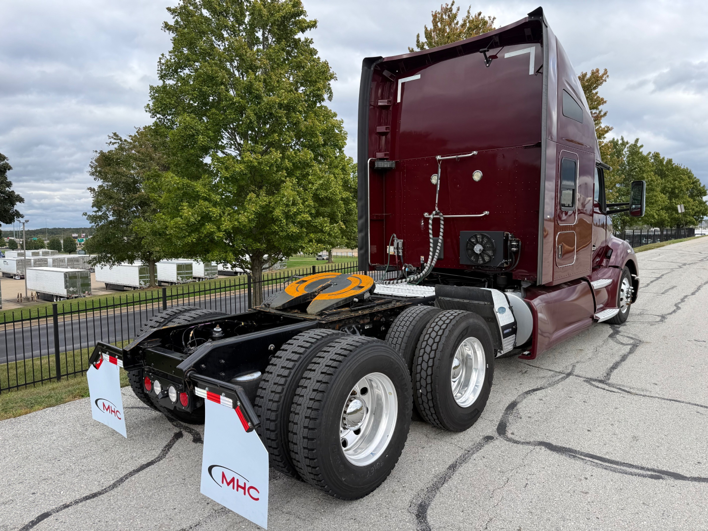 Truck chassis and cab of a 2021 Kenworth T680 in a yard, with rear wheel assembly and fifth wheel visible.