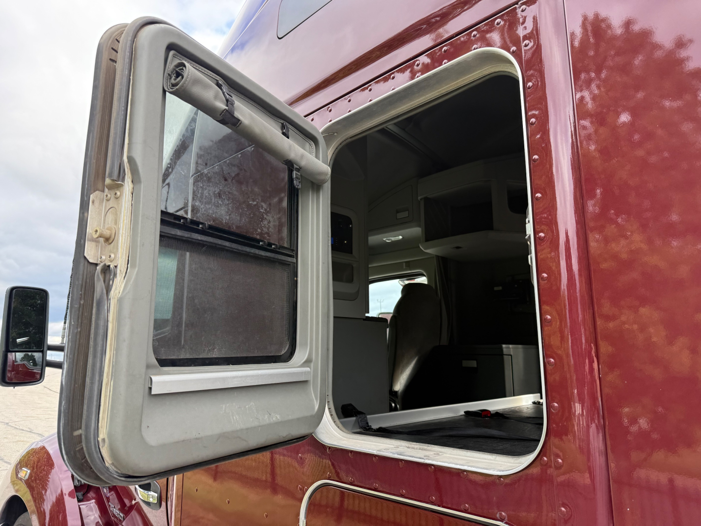 Kenworth T680 truck cab door open showing sleeper cockpit and interior dash.