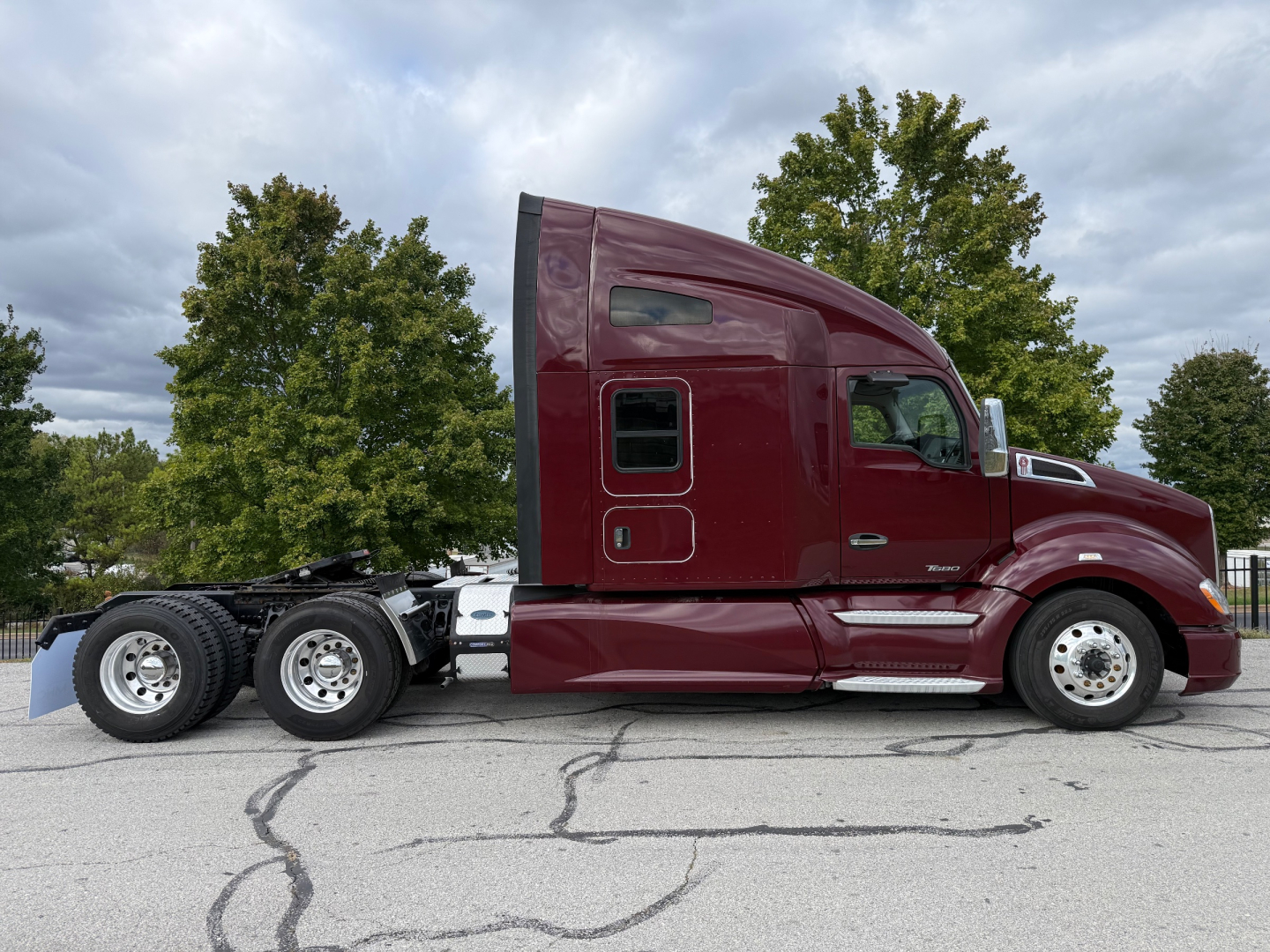 Kenworth T680 semi-truck side profile showing maroon cab and sleeper, with dual rear axles and chrome steps.