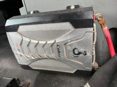 Cobra fuel or auxiliary device mounted in a Kenworth T680 engine bay with red battery cable and labeled components visible.
