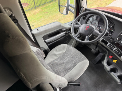 Kenworth T680 interior showing steering wheel and dashboard with gray cloth seat and controls.