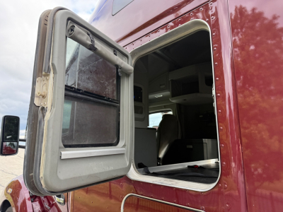 Kenworth T680 truck cab door open showing sleeper cockpit and interior dash.