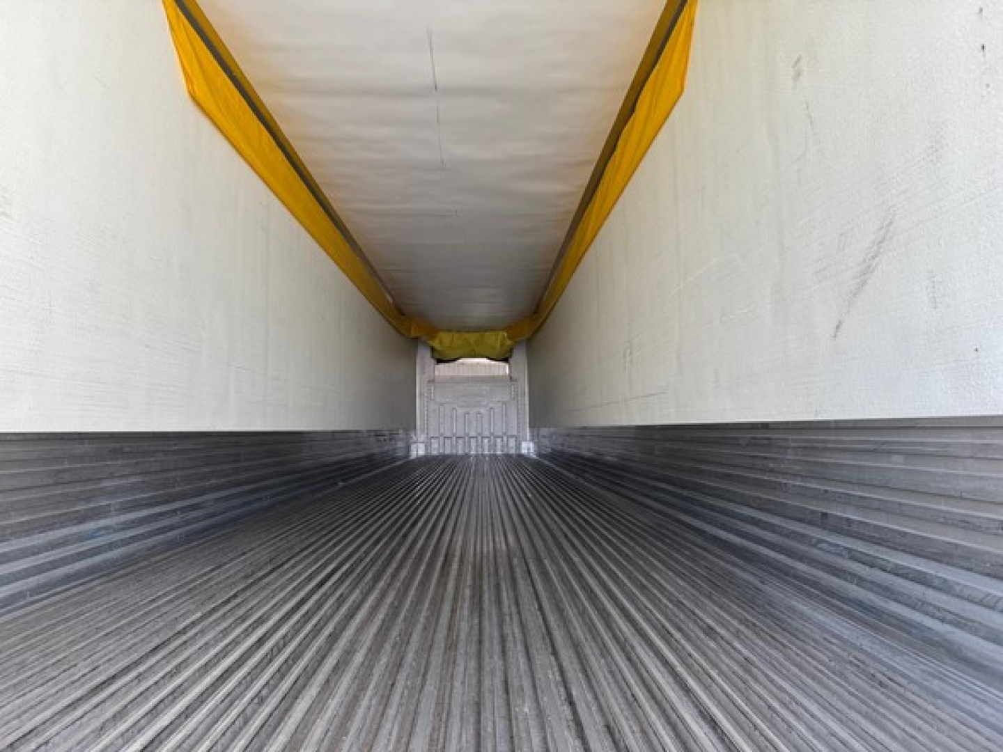 Trailer interior showing ribbed metal floor and white ceiling and yellow curtain side at rear of 2022 Utility 3000R.