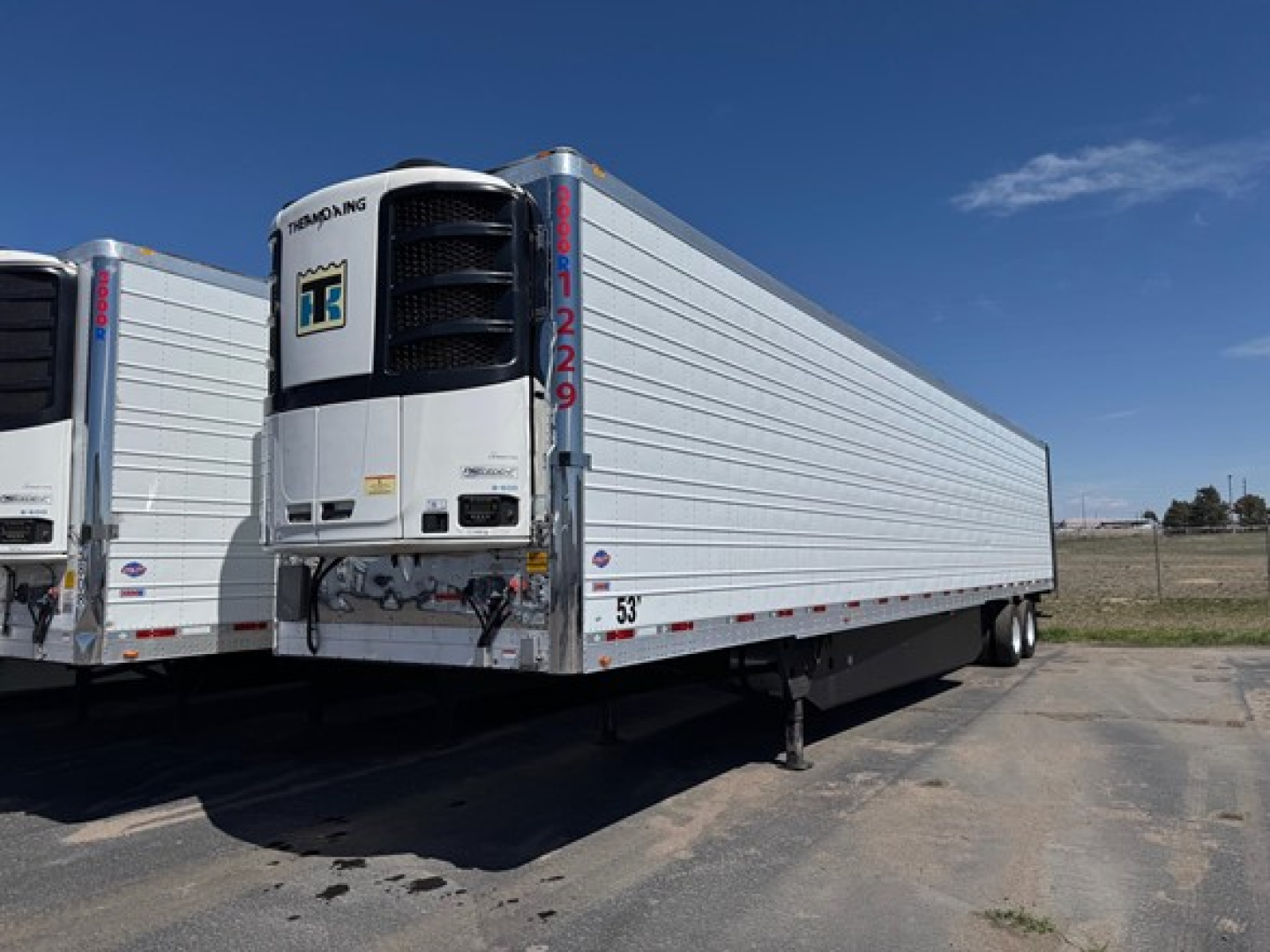 Utility 3000R trailer with vertical refrigeration unit at front, silver ribbed sides, rear doors, landing gear, and one visible front corner.