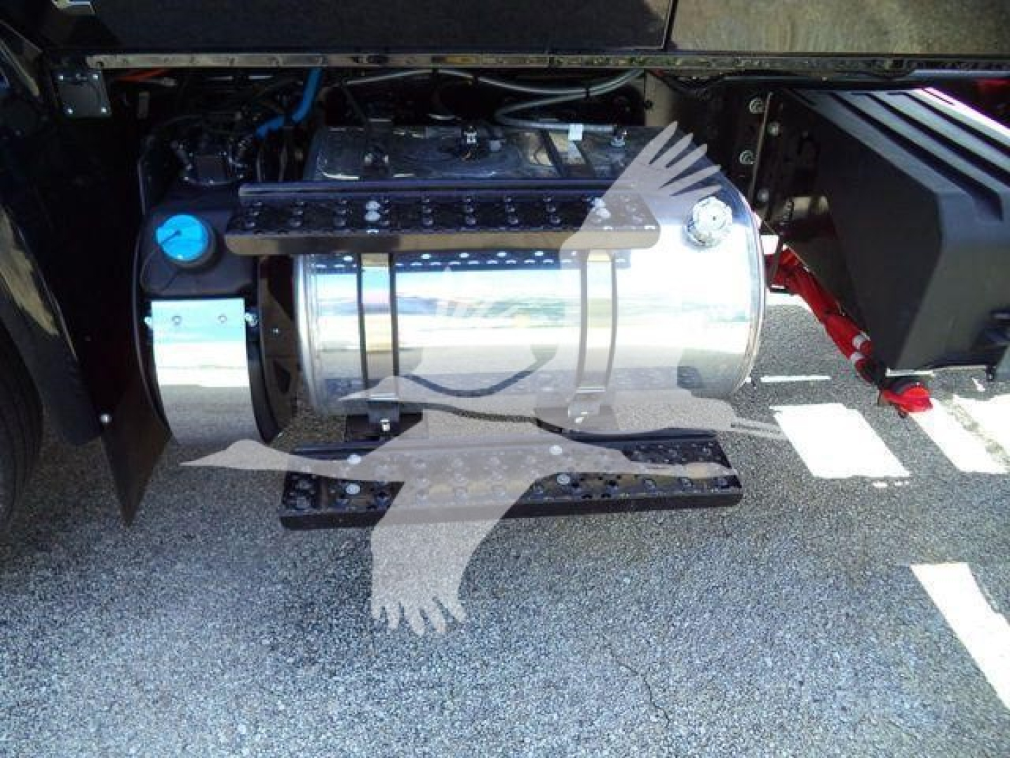 Truck engine bay showing chrome fuel tank with blue cap and surrounding components in a row of a 2027 International MV rollback truck.