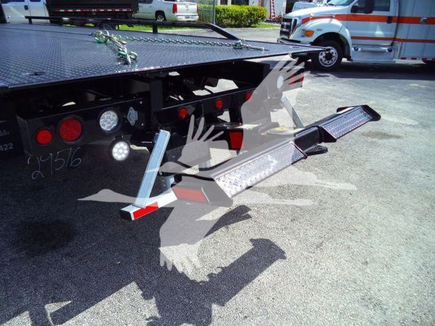Flatbed tow truck wheel-lift/dolly with loading ramps extended showing platforms and safety lights.