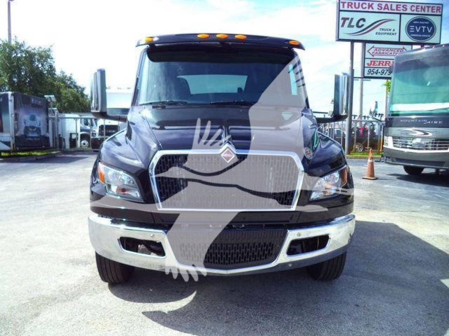 Front view of a black International MV truck with chrome grille and white bumper, dealership lot in background; no visible model text on the image.