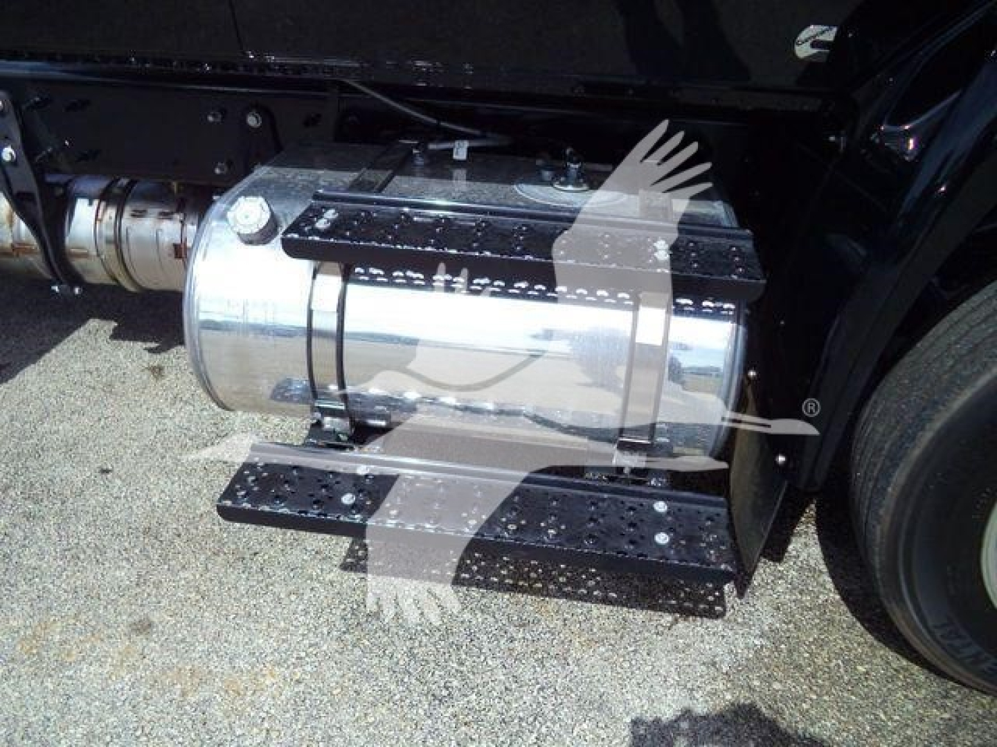 Truck fuel tank and undercarriage view showing chrome cylindrical fuel tank with black steps and mounting brackets.