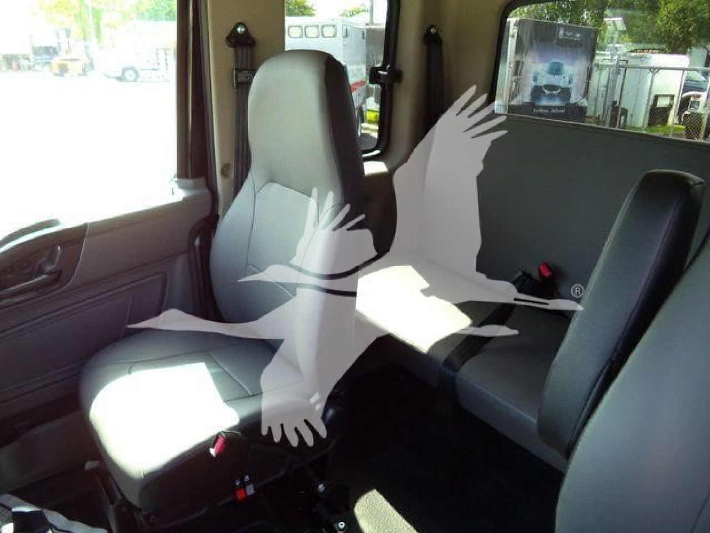 Interior of a 2027 International MV rollback truck showing front passenger seat and rear bench seat with light gray upholstery.