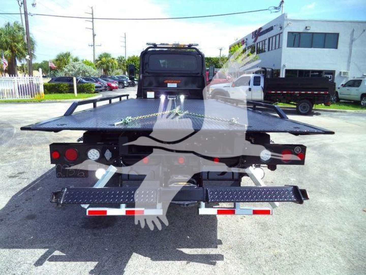 Truck bed with flatbed/tow equipment and rear lights visible in a dealership lot.