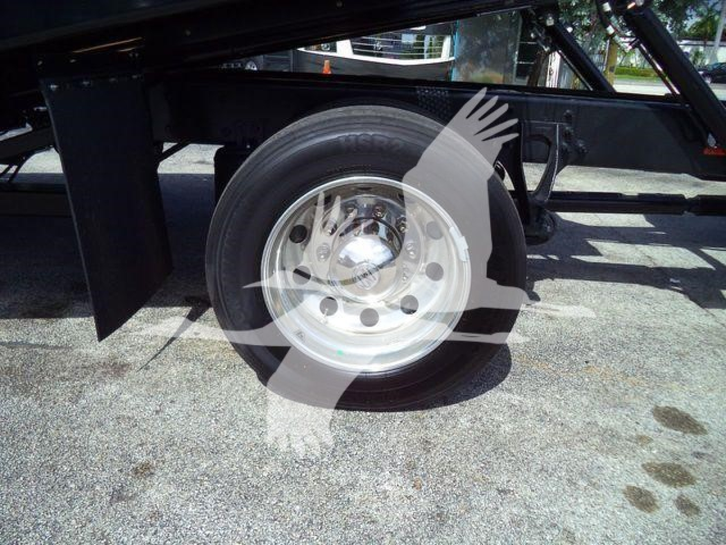 Wheel and suspension area of a truck trailer frame with a stainless steel rim and black axle components.