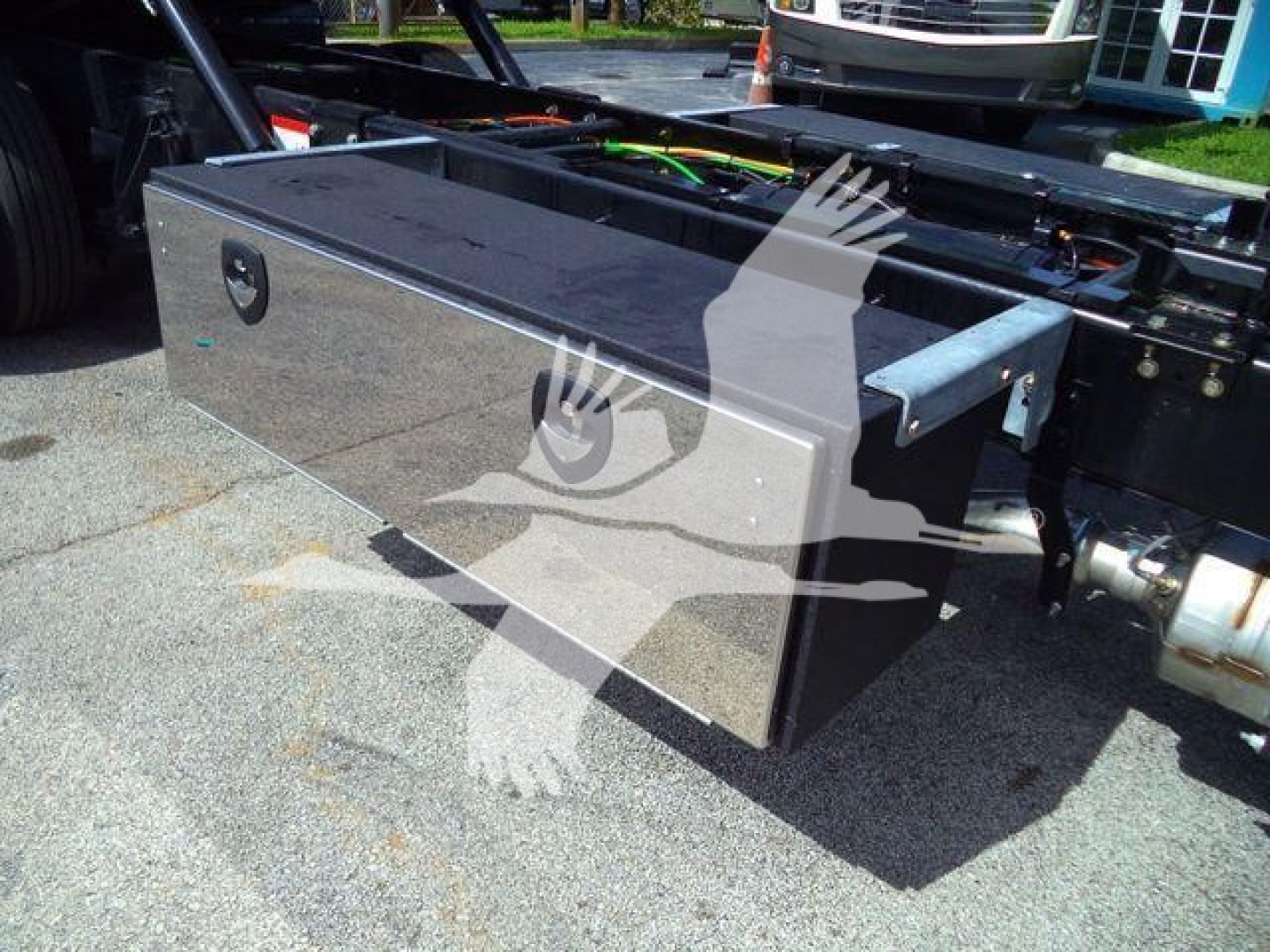 Metal toolbox with reflective surface mounted on a truck chassis showing a rectangular aluminum storage box with latch and mounting rails.