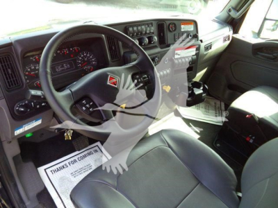 Interior of a truck cab with steering wheel, dashboard, and driver seat. Visible text includes 'Thanks for coming in' on a paper mat, and various gauges and controls on the dashboard.