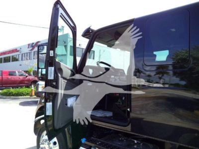 Truck cab door open showing interior with side steps; black exterior with reflection; forward rolling area; other vehicles in background.