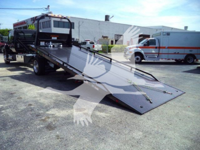 Tow truck rollback bed with hydraulic winch and ramps, black steel platform, truck cab in background, MV607EXCABBLK stock number.