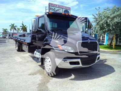 Truck showing 2027 International MV rollback truck with black cab and flatbed, front grille, headlights, and side mirrors.