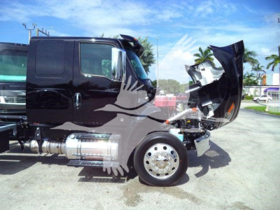 Truck cab with hood open showing engine compartment and side view mirrors; International MV series truck in black.