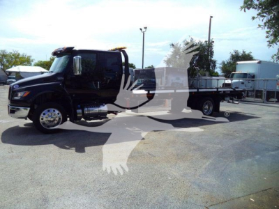 International MV rollback truck with black cab and flatbed shown in side view.