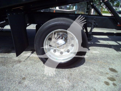 Wheel and suspension area of a truck trailer frame with a stainless steel rim and black axle components.