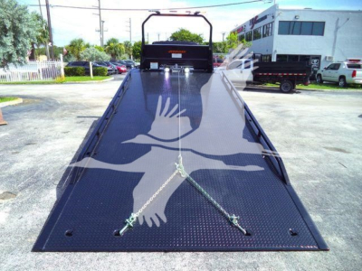 Tow truck rollback flatbed with black diamond-plate surface showing tiedown anchors and a rear ramp, MV607EXCABBLK stock number.