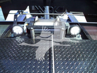 Trucks equipment bay with two round headlights and a central winch/assembly. Visible labels and mesh platform, stock number MV607EXCABBLK.