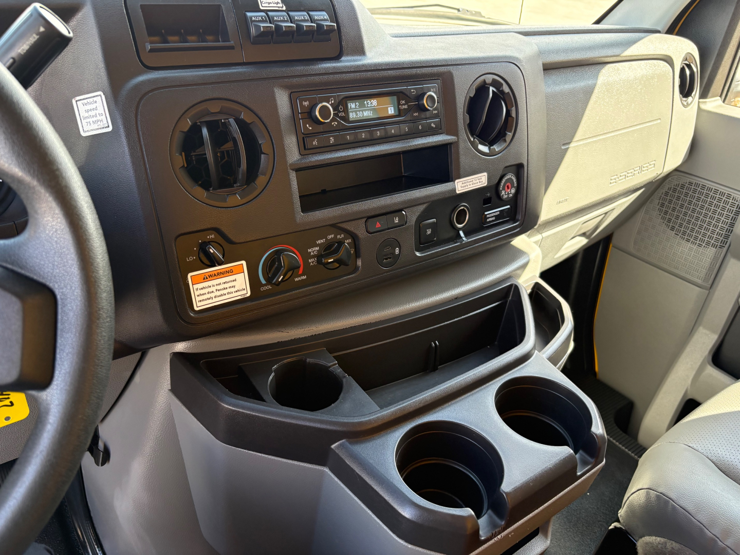 Ford E-350 van interior dash area with circular vents, radio, climate controls, cup holders and storage compartments visible.