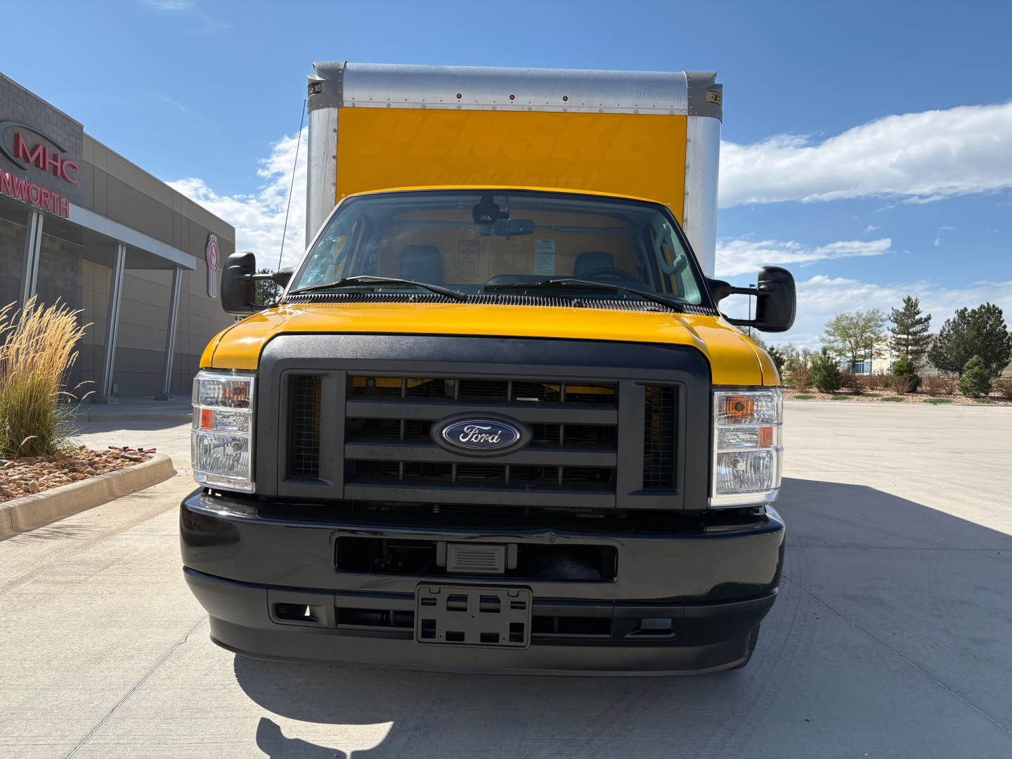Ford E-350 cutaway truck front view showing yellow cab and box, Ford emblem on grille, rectangular headlights, black bumper.