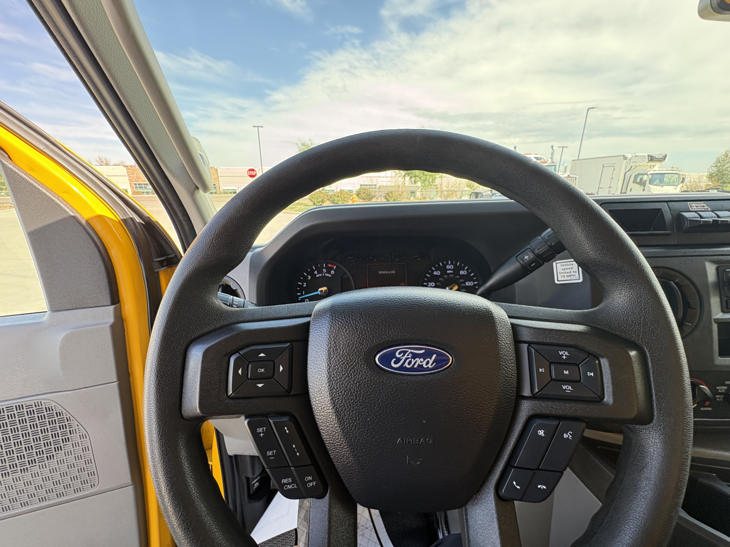 Steering wheel and dashboard of a 2022 Ford E350 cargo van showing Ford logo and control buttons.