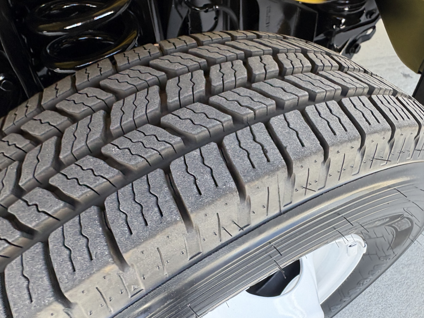Ford E-Series heavy-duty truck wheel and tire close-up showing tread pattern and wheel well; portion of suspension above the tire.