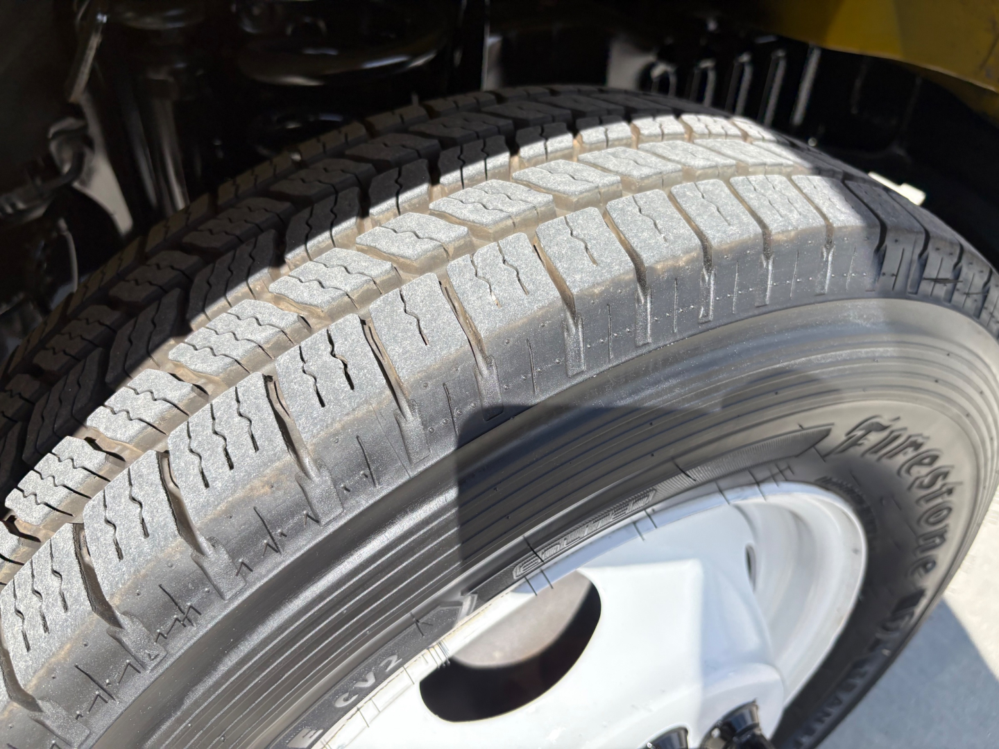 Truck wheel close-up showing Goodyear/All-Season tire with visible treads and rim, part of a Ford E-Series cutaway chassis.