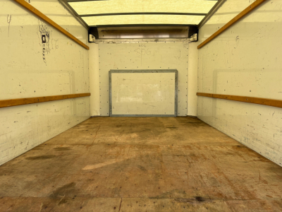Truck cargo area inside a 2022 Ford E350 box truck showing empty wood-lined walls and a rear ramp door.