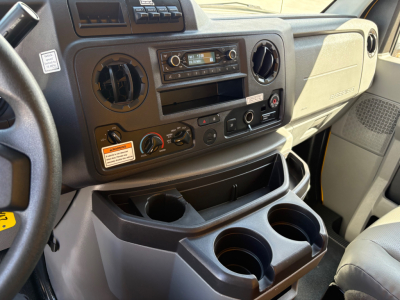 Ford E-350 van interior dash area with circular vents, radio, climate controls, cup holders and storage compartments visible.