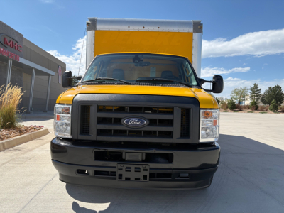 Ford E-350 cutaway truck front view showing yellow cab and box, Ford emblem on grille, rectangular headlights, black bumper.