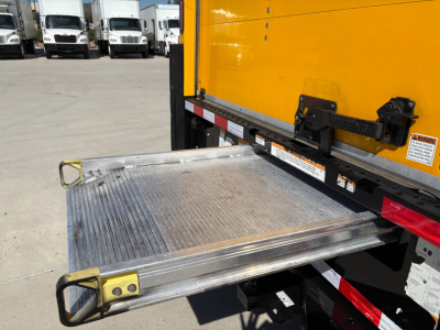 Ford E-350 step/fold-out loading ramp extending from side of yellow cutaway truck with aluminum surface and warning stickers.