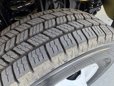 Ford E-Series heavy-duty truck wheel and tire close-up showing tread pattern and wheel well; portion of suspension above the tire.