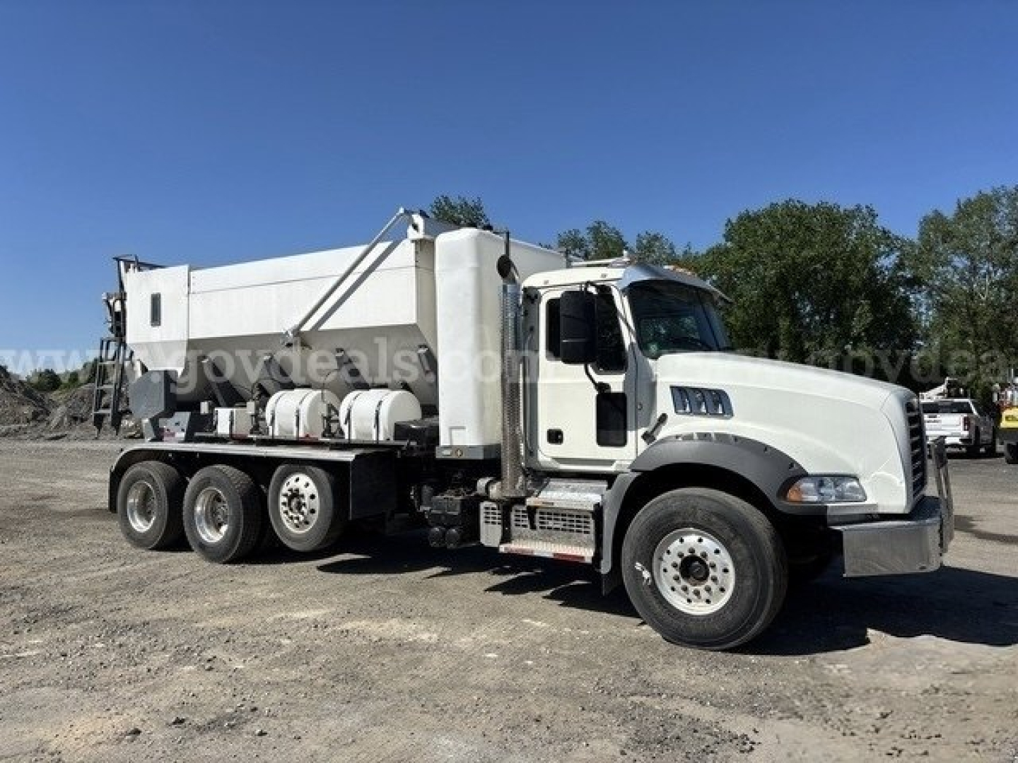 Mixer truck side view showing large white cement mixer unit on a Freightliner chassis with multiple rear axles and black chassis.
