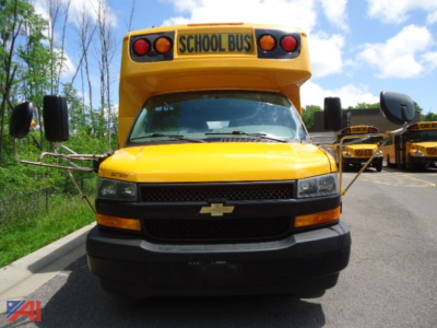 School bus front view showing bright yellow Chevrolet Express 4500 with 'SCHOOL BUS' sign and molded bumper.