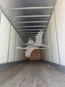 Trailer interior showing empty cargo space with wood bulkhead at far end and metal side rails.