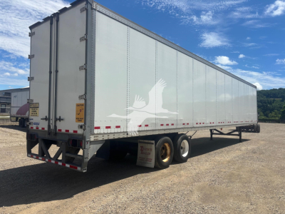 Trailer side view showing a 2017 Vanguard VXP box trailer with dual rear doors, tandem axles, white exterior and reflective tape.