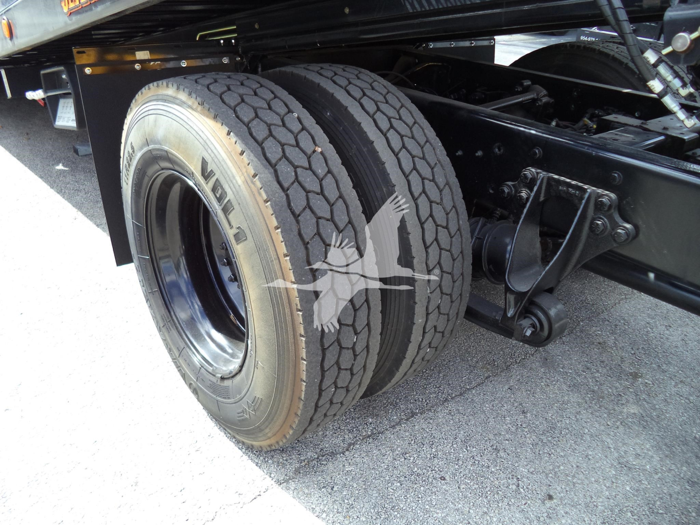 Double rear wheels of a rollback truck showing dual-tire assembly and suspension components.