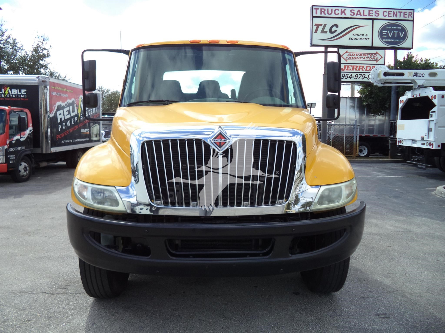 Front view of a yellow 2019 International 4300 rollback truck with a large chrome grille and black bumper.