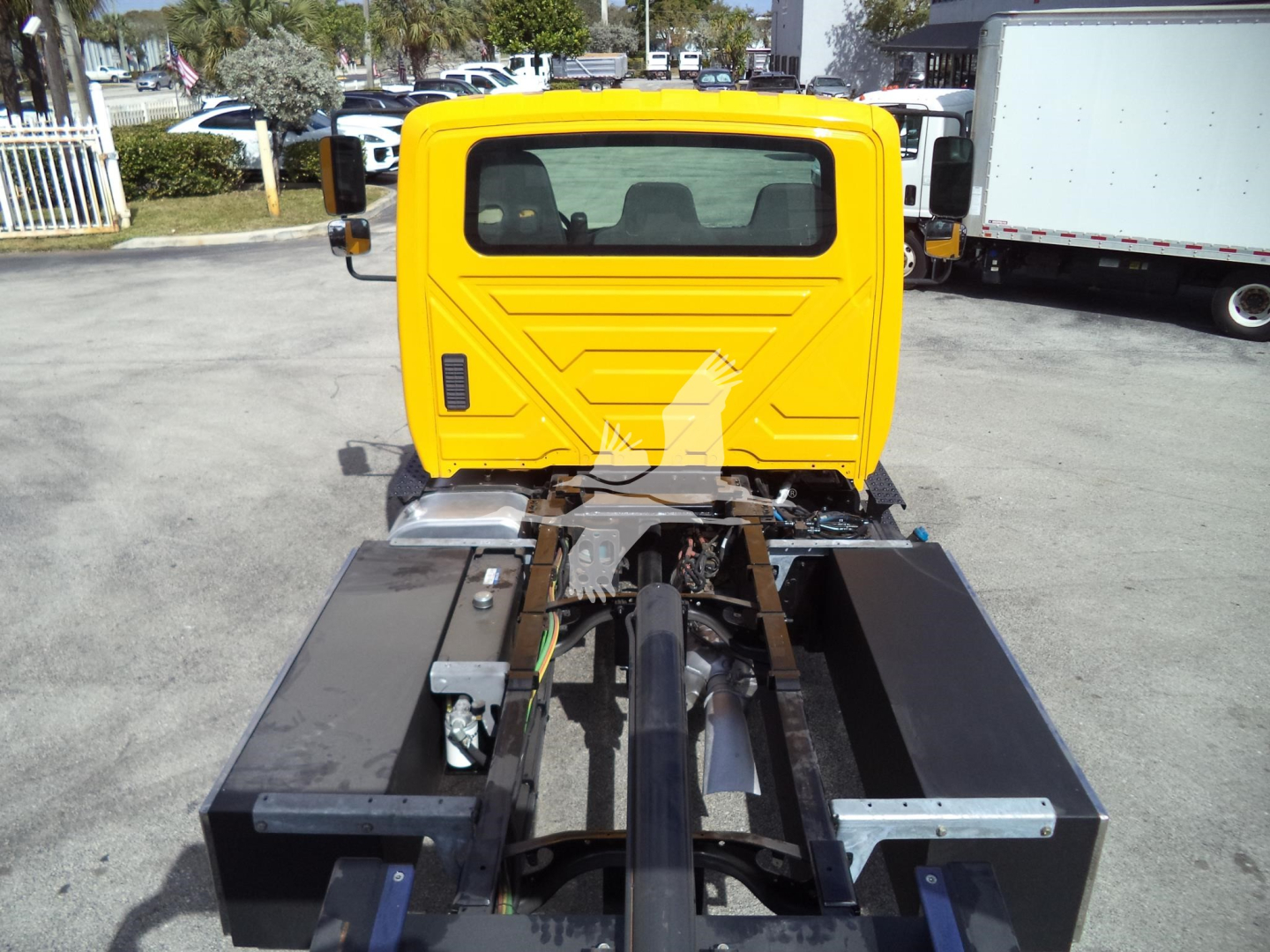 Truck cab rear view on a yellow International 4300 rollback with chassis and hydraulic hose visible