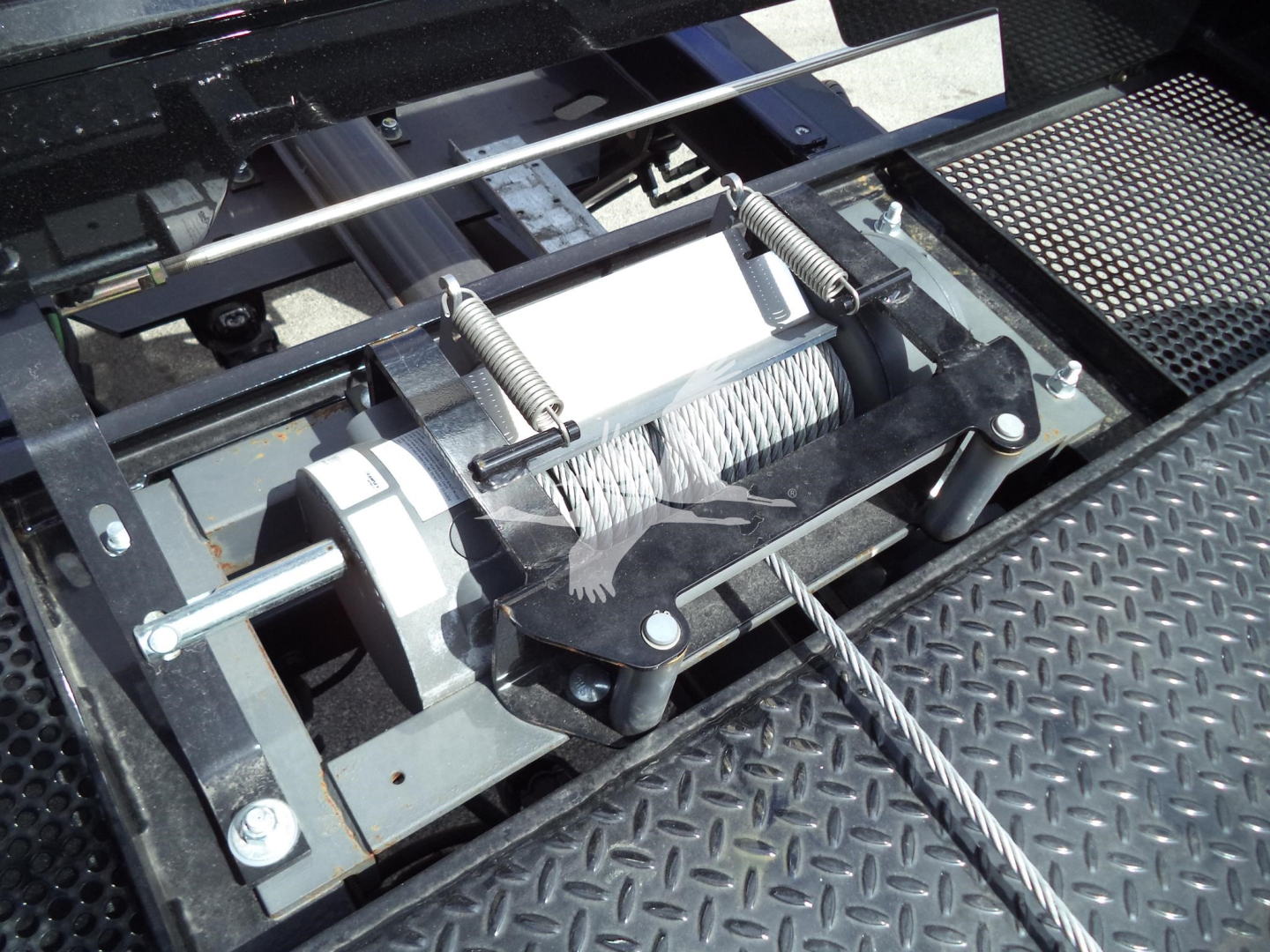 Winch mechanism with steel cable and spool in truck bed, tight assemblies and mounting brackets visible.