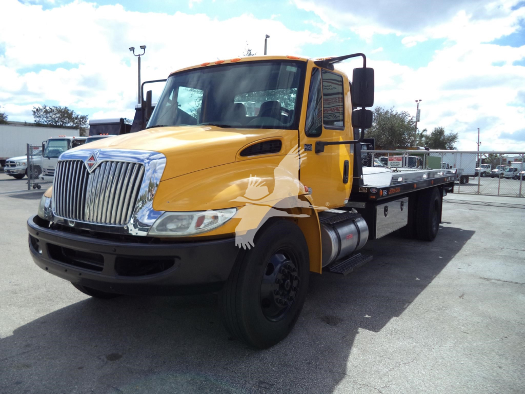 2019 International 4300 tow truck/rollback with yellow cab and flatbed, front grille and headlights visible.