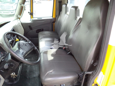 Interior of a 2019 International 4300 rollback truck showing front bench seat and steering wheel with yellow exterior.
