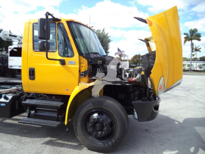 International 4300 rollback truck with hood open showing engine bay and front wheel, yellow cab, black components.