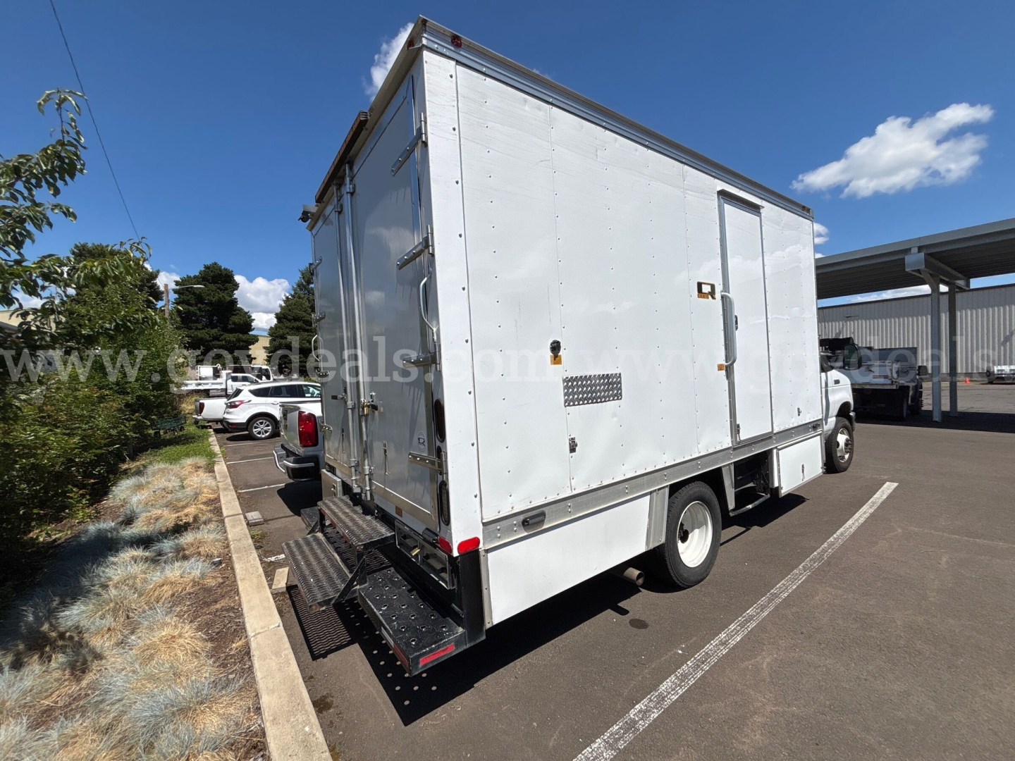Box truck rear view showing cargo box and rear entry doors on a white 2017 Ford Econoline with side ventilation and steps.