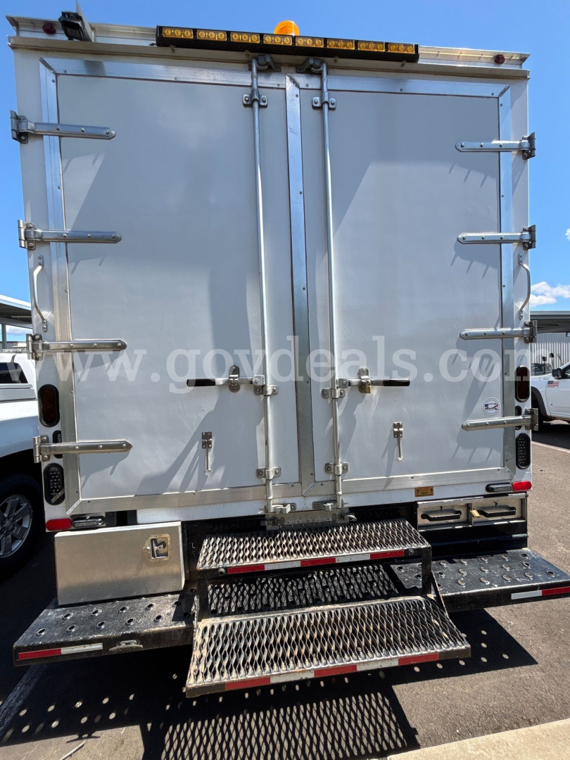 Ford Econoline box truck rear view showing two tall metal doors with latches, rear step bumper, and safety lights on top.