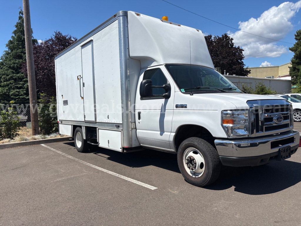 Ford Econoline box truck in a parking lot showing cargo box and cab with side door and orange clearance light on top.