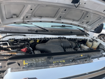 Ford Econoline engine bay with hood open showing air intake, battery, and various fluid reservoirs.